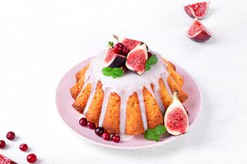Yeast cake topped with sugar icing, figs and cranberry on the white table