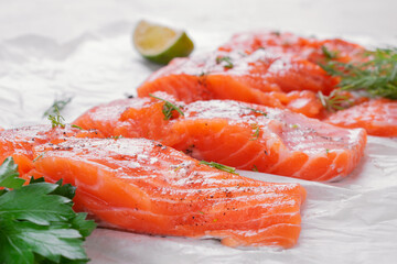 Raw trout steaks seasoned with lime juice, salt and pepper on parchment paper. Cooking red fish