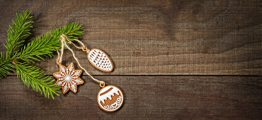 Christmas composition of a tree branch and three gingerbread on a wooden background