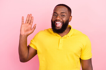 Photo of afro american cheerful happy young man wave hello good mood cool isolated on pink color background © deagreez