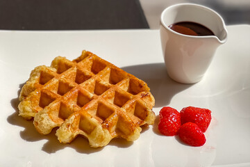 Belgian waffles topped with strawberries, and hot chocolate.