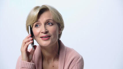 middle aged woman smiling during conversation on smartphone isolated on white.