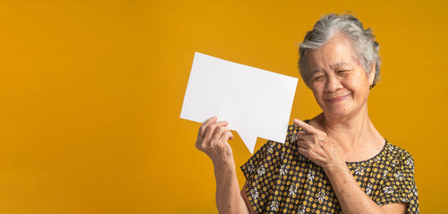 Concept of a paper speech bubble. An elderly Asian woman with short gray hair holding looking and...