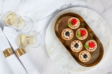 canape with black caviar and soured cream near glass with champagne