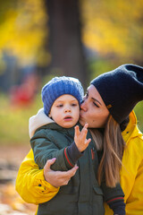 boy in autumn leaves looking with mom at ladybug