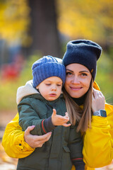 boy in autumn leaves looking with mom at ladybug