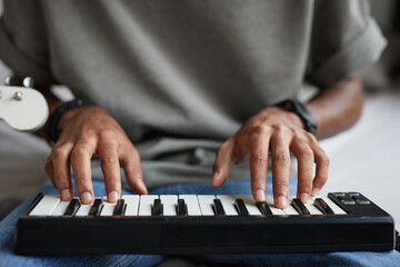 Close up of young African-American musician composing music, focus on hands at DJ keyboard, copy...