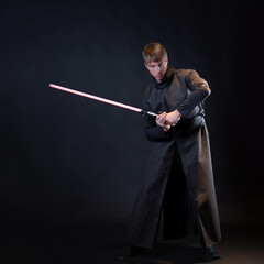 A villain with a red lightsaber, a young man in a long robe does fighting poses, fantasy or science...