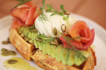 waffles with avocado and red fish are on the table
