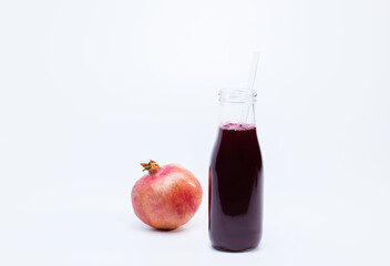 Ripe pomegranate with bottle of pomegranate juice on white background