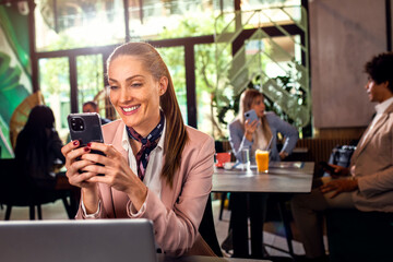 Business woman working at cafe using laptop and smartphone.