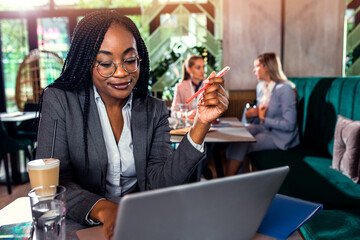 Young business woman working at cafe using laptop.