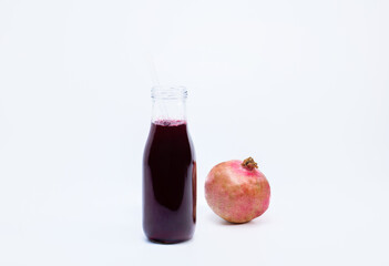 Ripe pomegranate with bottle of pomegranate juice on white background	