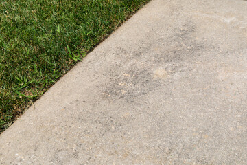 Obraz premium Concrete sidewalk with light staining set diagonally alongside green grass, well tended, horizontal aspect