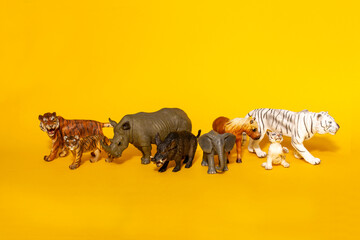 toy animals on a yellow background, tiger, wild boar, elephant, rhino
