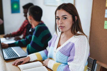 Students learning with books and laptop computer together inside classroom