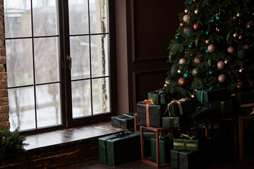 Christmas tree in home interior near big window in high key. Presents box near the decorated tree
