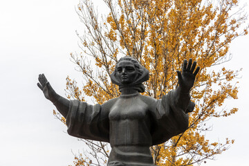 Monument to mother in the park on a background of yellow leaves