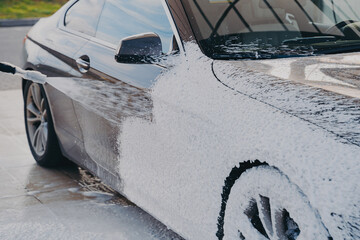 High-pressure car cleaning, spraying special wash soap on vehicle with pressure washer outdoors