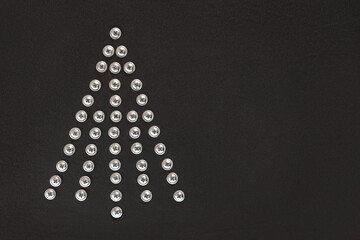 Christmas tree of screws on a black background. Flat lay. Copy space. Unusual Christmas tree made of construction tools. Creative Industrial greeting card. Build, repair concept. Workshop. Top view