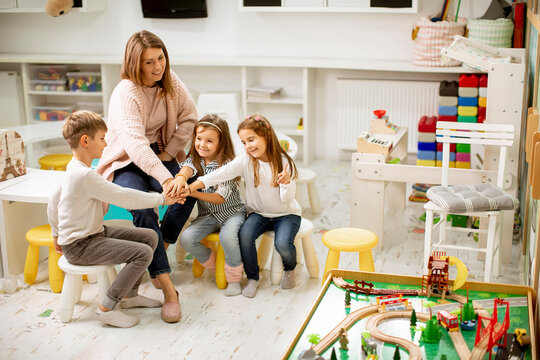 Cute Preschool Kids Put Hands Together With Their Nursery Teacher