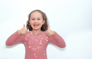 Cute cheerful positive little girl with curly tails, showing two thumbs up. Isolated on a white background