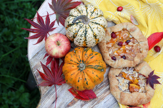 Colorful photo of pumpkin galettas and squashes on a table. Still life food photo with seasonal vegetables and pastries. Eating fresh concept. 
