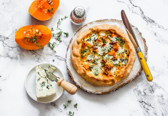 Delicious seasonal pastries - honey pumpkin, leek, gorgonzola cheese quiche on a light background,...