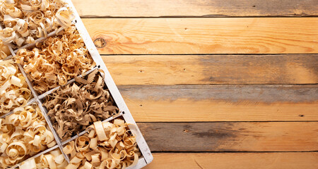 Wood shavings in box on table background. Wooden shaving at old plank board