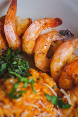 Traditional bright shrimp risotto in a bowl on a table in a restaurant with a beautiful decor in a dark key close-up.