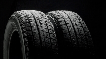 Winter Car tires with snow close-up wheel profile structure on black background. 