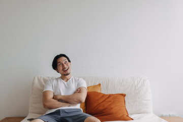 Asian man feels surprised and shocked at empty copy space wall in living room.