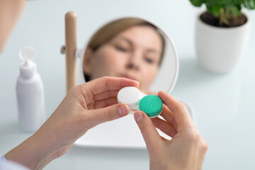 A woman holds a contact lens container in her hands