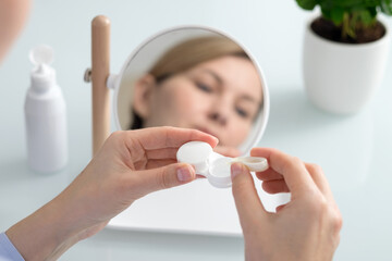 A woman holds a contact lens container in her hands
