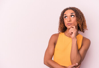 Young latin transsexual woman isolated on pink background looking sideways with doubtful and...