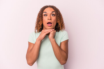 Young latin transsexual woman isolated on pink background praying for luck, amazed and opening mouth looking to front.