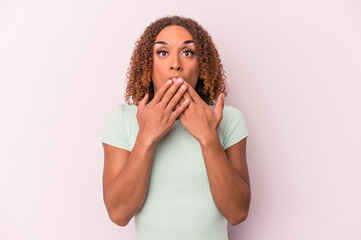 Young latin transsexual woman isolated on pink background shocked, covering mouth with hands, anxious to discover something new.