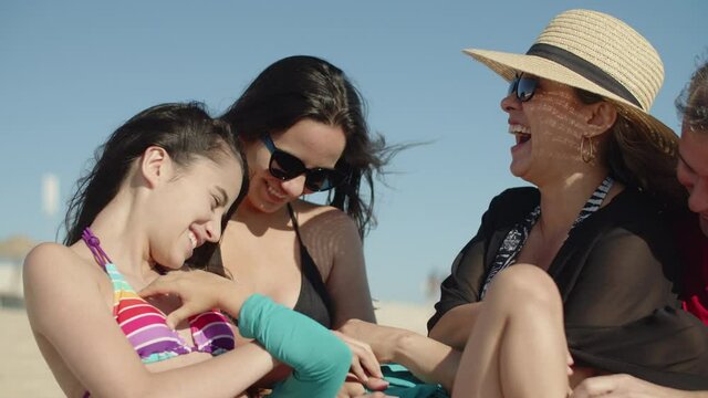 Happy family holding boy in arms and tickling his on summer day. Medium shot of smiling Caucasian mother, father, son and daughters having fun during summer at sea. Emotion, togetherness concept 