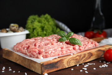 Raw chicken minced meat with basil and salt on wooden table, closeup