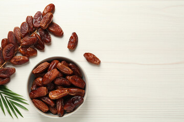 Flat lay composition with tasty sweet dried dates on white wooden table. Space for text