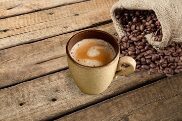 Hot coffee in a white coffee cup and many beans placed around