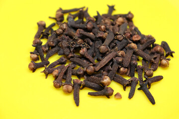 The pile of cloves is on a black background on a yellow plate