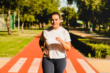 Body positive plus-size plump woman athlete jogging running in fitness outfit, losing weight while...