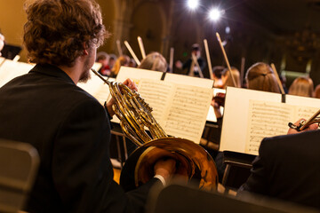 A view from behind a French horn player towards the front of a symphony orchestra seeing his music...