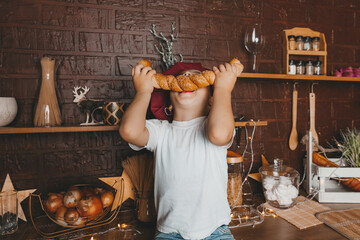 Little chef. Little kid wearing a chef's hat with pastries, buns, bread and bagels. Boy eating a...