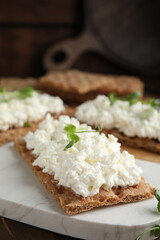 Crispy crackers with cottage cheese and microgreens on board, closeup
