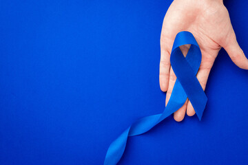 Blue ribbon cancer. Awareness prostate cancer of men health in November. Blue ribbon in hands...