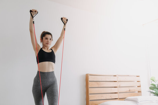 Asian Woman Do Resistance Band Upper Chest Press Workout In Her Bedroom.