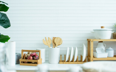 Interior design of cozy kitchen room at comfortable home in minimal style with wooden equipment of forks, spoons, pot and ingredients in wood and white colors. House Decoration and Renovation Concept.