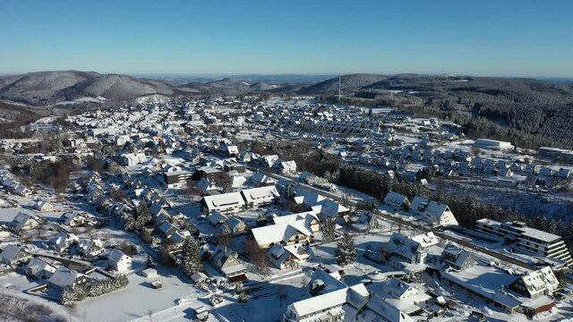 Air video shows the place Winterberg in winter. Snow covers the landscape. In the background are the Rothaar mountains. Real time.